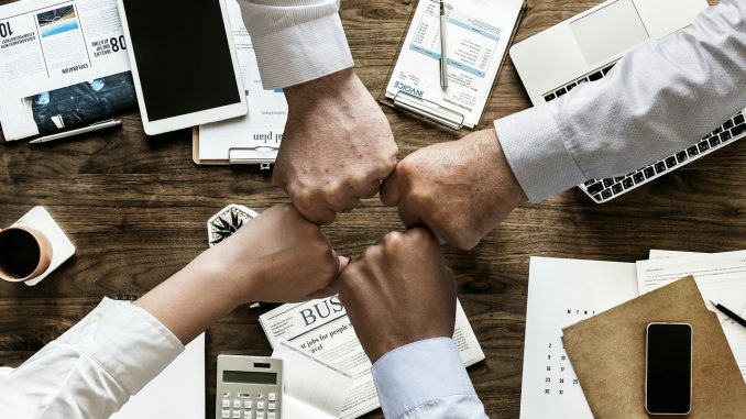 esprit-equipe quatre poings serrés au dessus d'une table avec matériel de travail