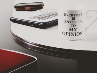 Tasse blanche avec inscription posée sur un bureau avec ordinateur