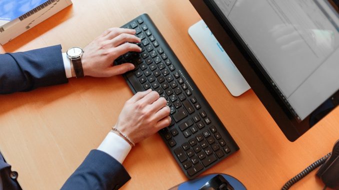 mettre-en-place-logiciel-de-santé personne en costume qui tape sur un clavier d'ordinateur de bureau