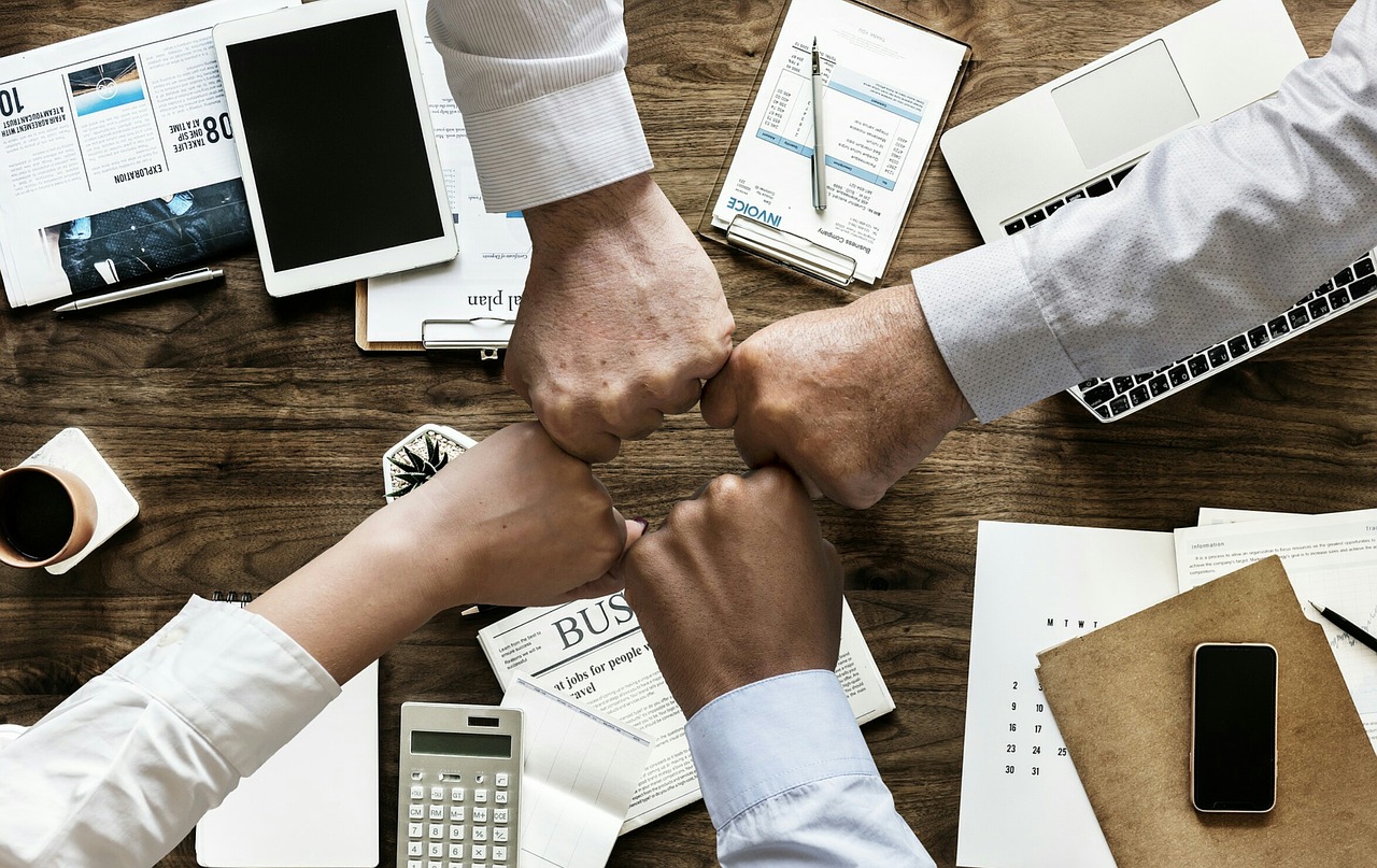 quatre poings serrés au dessus d'une table avec matériel de travail