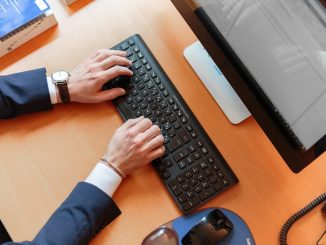 personne en costume qui tape sur un clavier d'ordinateur de bureau