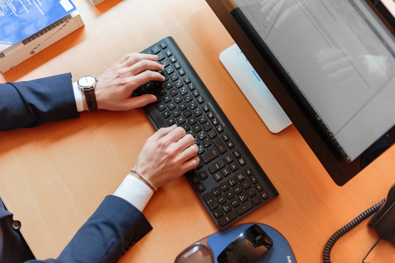 personne en costume qui tape sur un clavier d'ordinateur de bureau